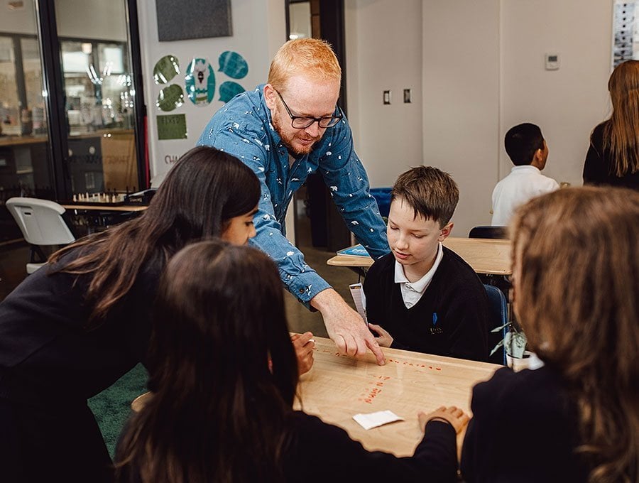 A teacher and middle school students working on a math problem together.