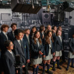 A group of Urban Academy students, in two rows, singing in a recording studio.