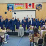 Urban Academy class of 2025 tossing their caps in the air at commencement.